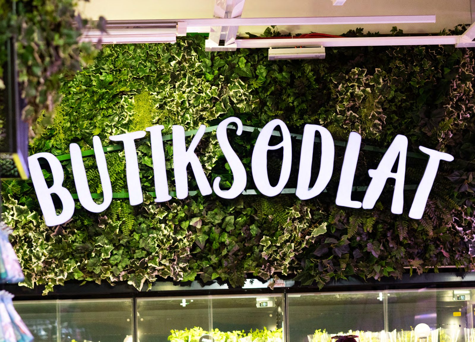 Skylten Butiksodlat på en växtvägg ovanför odlingen